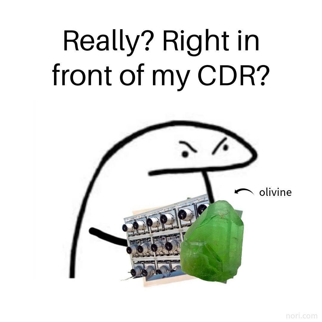 A simple doodle of an annoyed blob holding a direct air capture unit and a green olivine crystal, with the text "Really? Right in front of my CDR?"