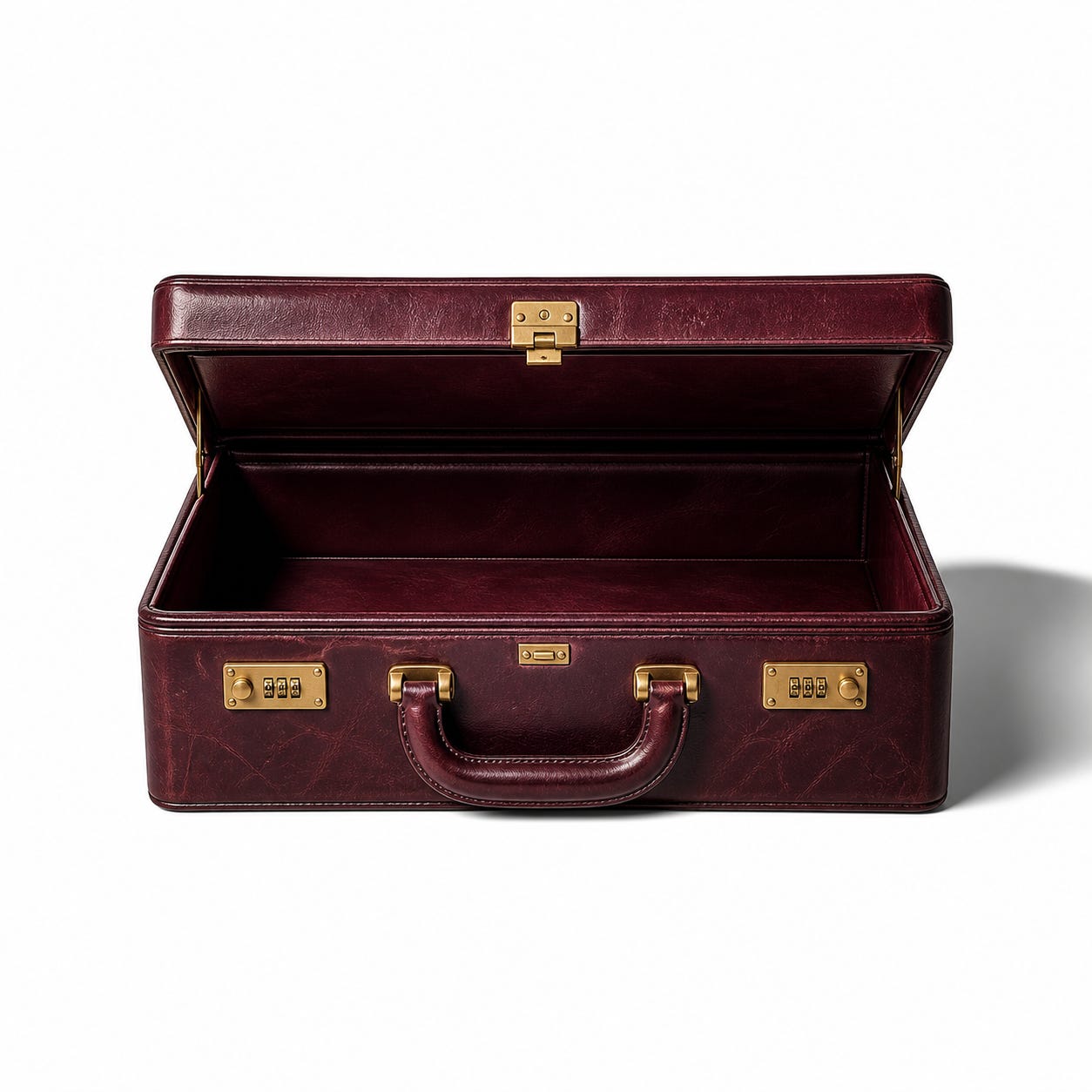 An open deep oxblood leather briefcase with brass fittings sits centred on a white studio background, empty inside, with soft light from the upper left casting a shadow to the right.