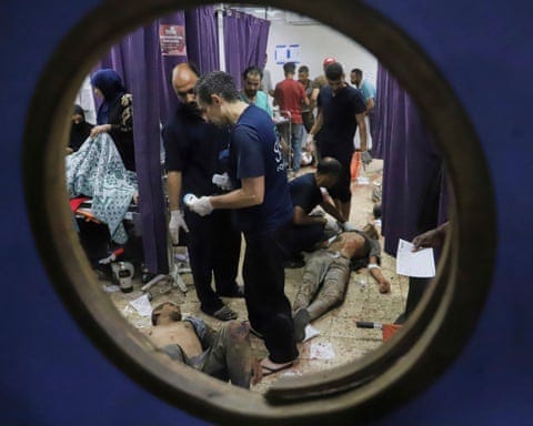 A view through a porthole style window in a door showing a chaotic scene with patients lying on the floor
