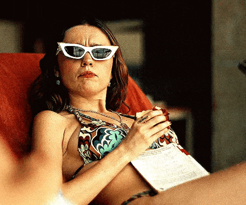 a woman in a bikini is wearing sunglasses and holding a piece of paper .