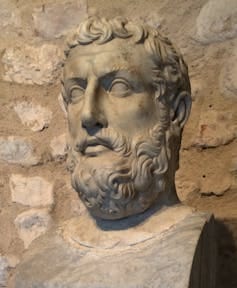 A stone bust of a man with curly hair and a beard.