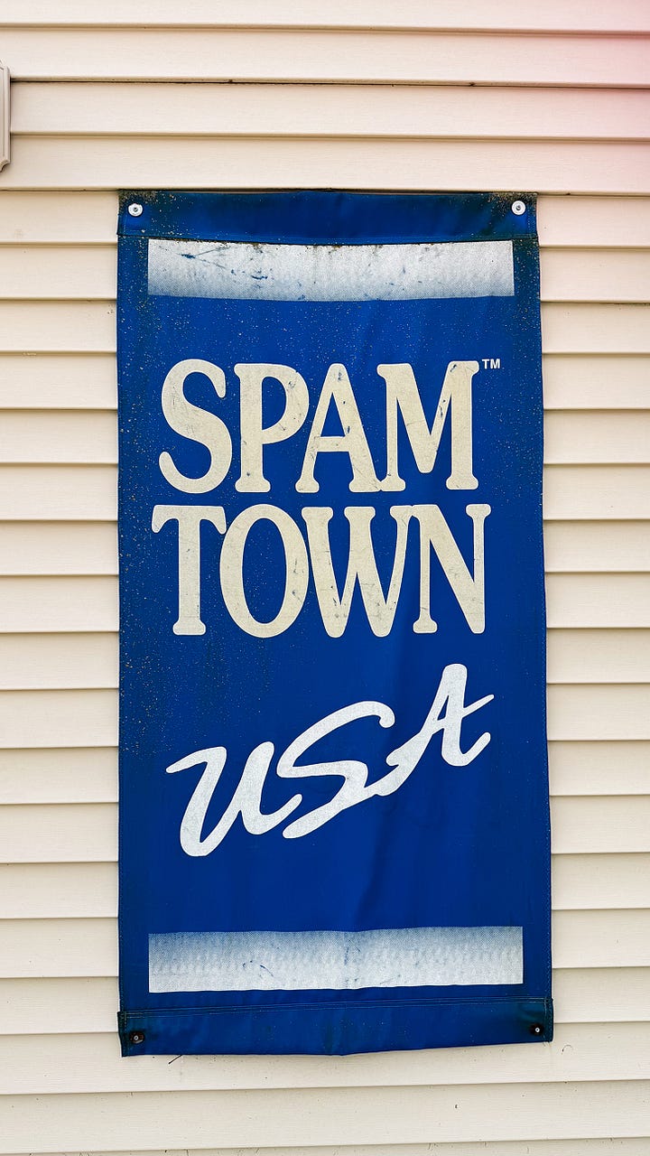 A blue banner reading "SPAM TOWN USA" next to a photo of a devoured SPAM omelet.