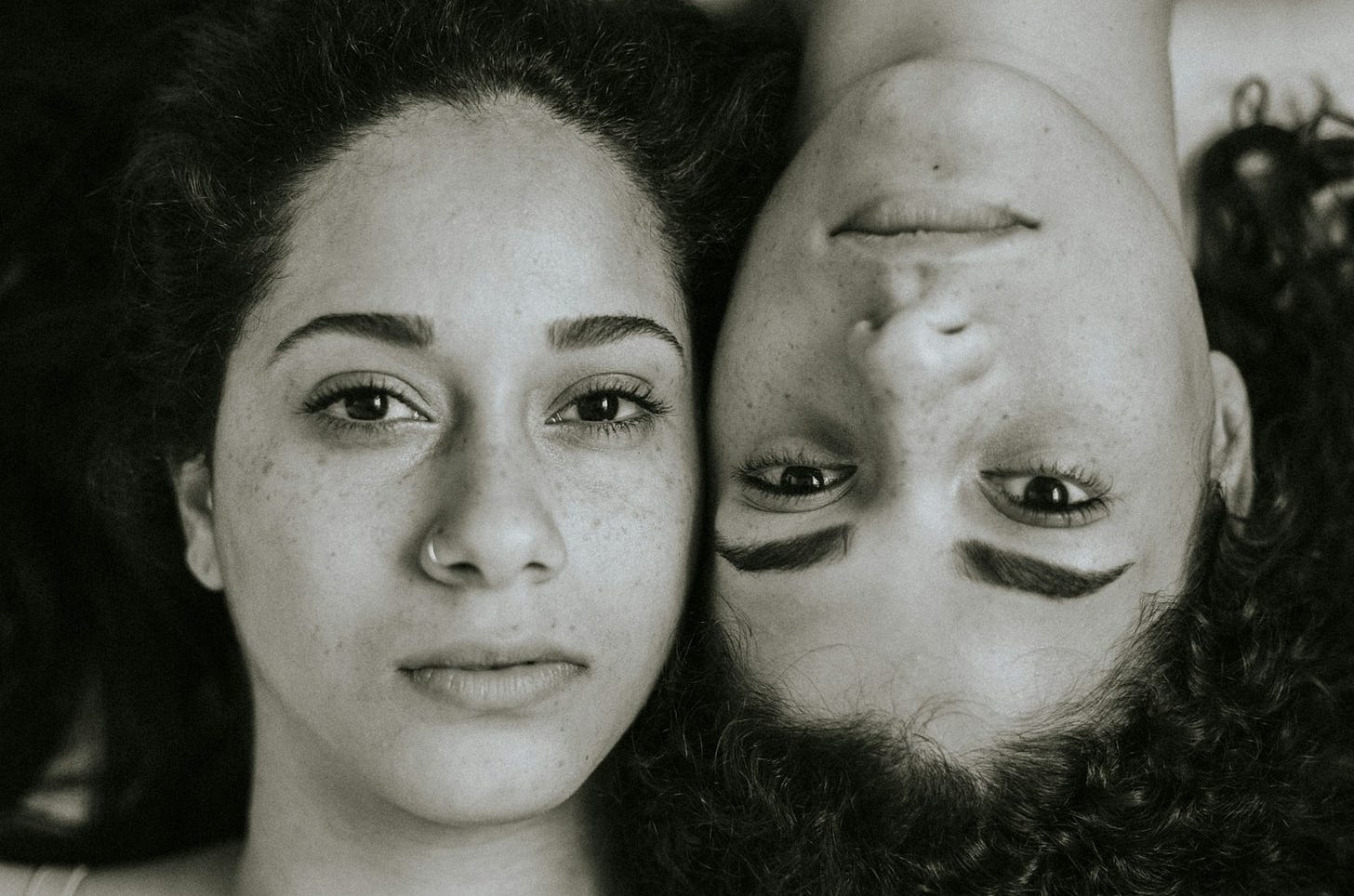 two women are laying down with their heads together