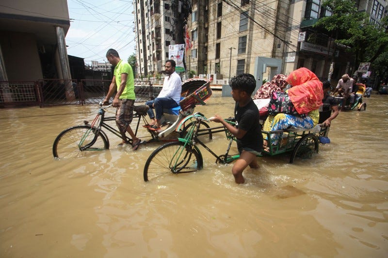 Rickshaw pullers transport customers along a knee-high flooded street Rickshaw pullers transport customers along a knee-high flooded street