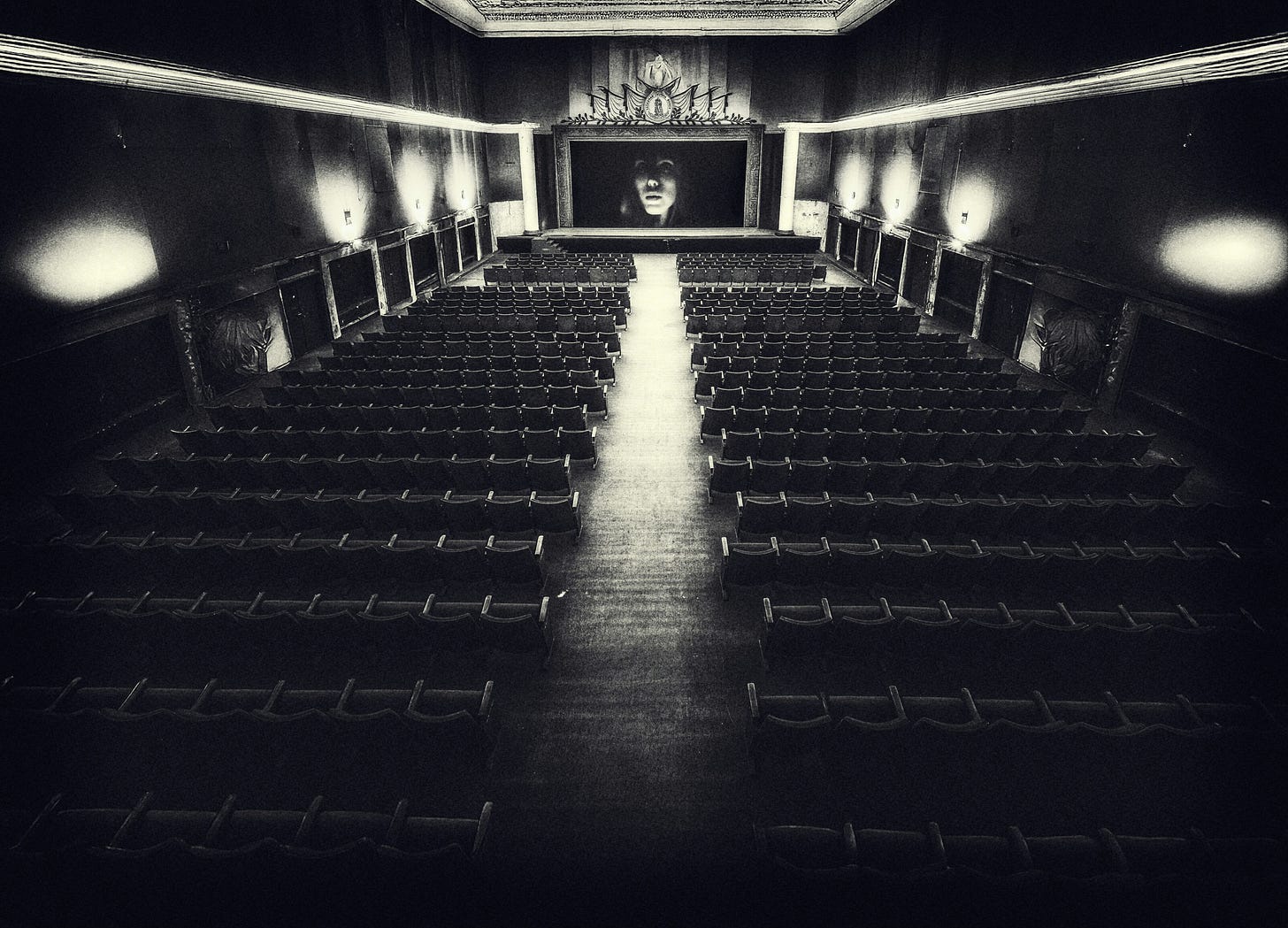 An empty auditorium with a single face staring from the stage