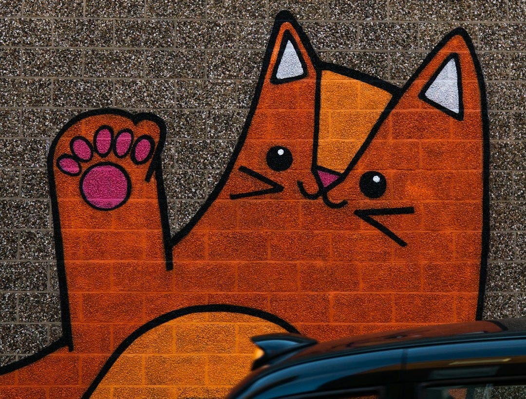 a black car parked in front of a brick wall with a picture of a cat