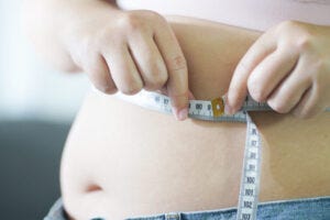 Obese Woman with fat belly in dieting concept. Overweight woman touching his fat belly and want to lose weight. Fat woman her waist with a centimeter. Shape up healthy stomach muscle and diet lifestyle concept.