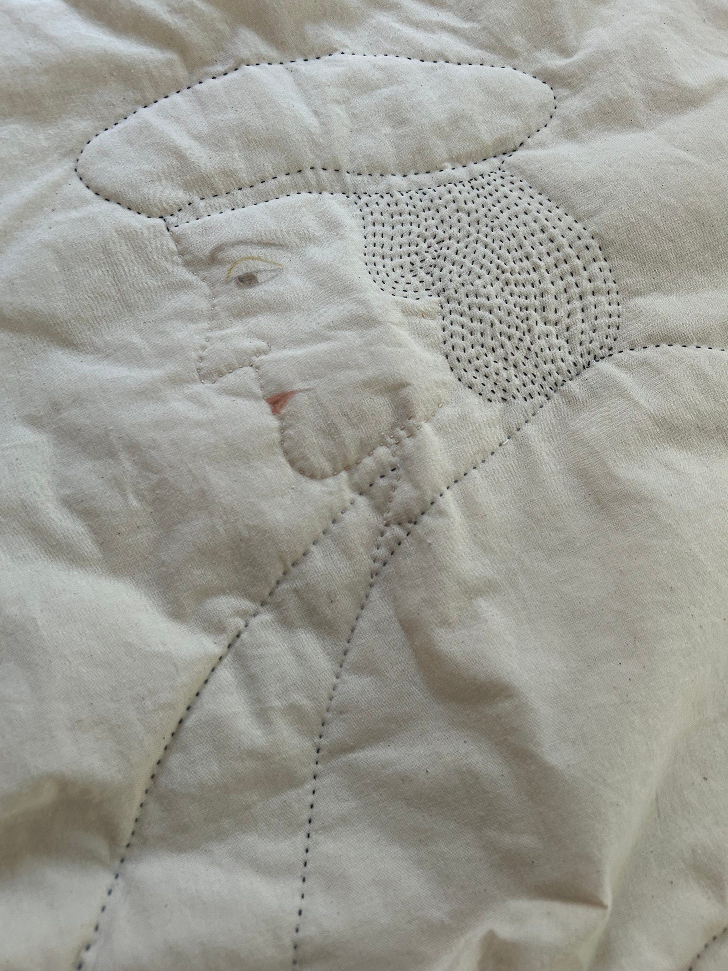 A quilted profile of Thomas Cromwell wearing a cap. His hair is tightly stitched, the rest is in outline. He has small eyes and a tight mouth, painted on cream calico. 