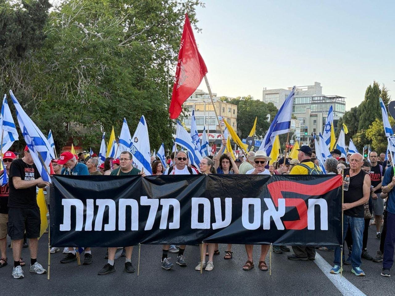 Protesters march along the streets of Haifa, Israel, carrying Israeli flags and yellow flags for the hostages. The sign says "Enough with the wars" following Israel's 12-day conflict with Iran and the war in Gaza, which has surpassed 630 days. The red flag is an anti-government protest symbol. Protesters march along the streets of Haifa, Israel, carrying Israeli flags and yellow flags for the hostages. The sign says "Enough with the wars" following Israel's 12-day conflict with Iran and the war in Gaza, which has surpassed 630 days. The red flag is an anti-government protest symbol.