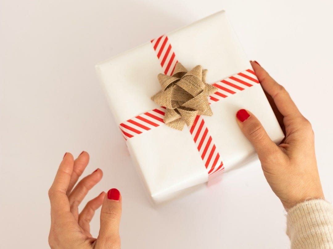 person holding white and red gift box person holding white and red gift box