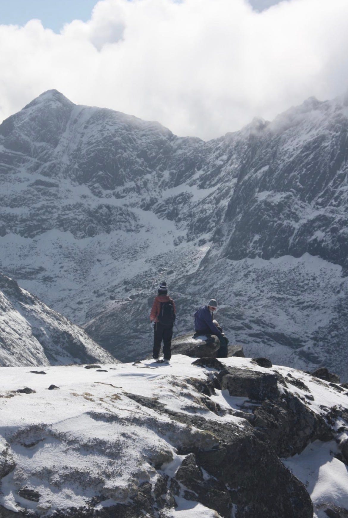 Two people sitting on the edge of a mountain