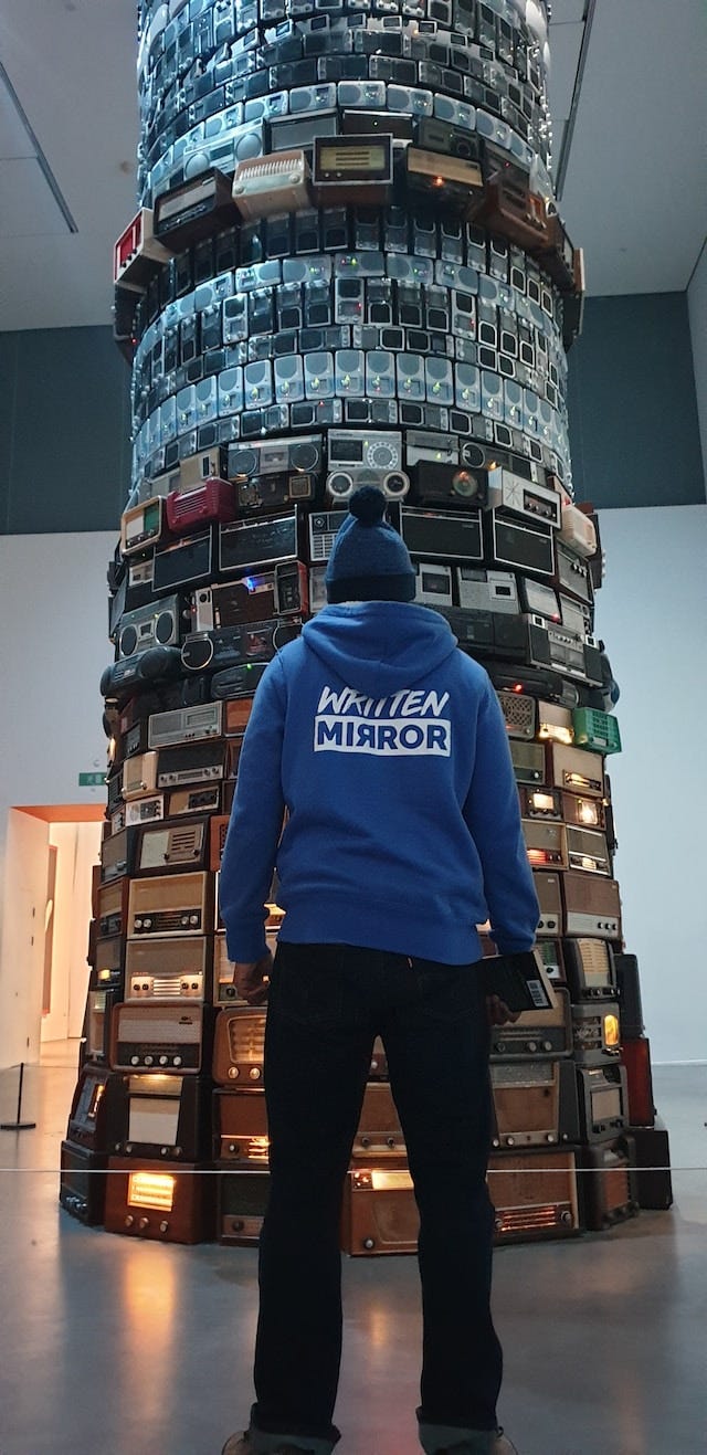 A man standing in front of a large tower that scales upwards. A man standing in front of a large tower that scales upwards.