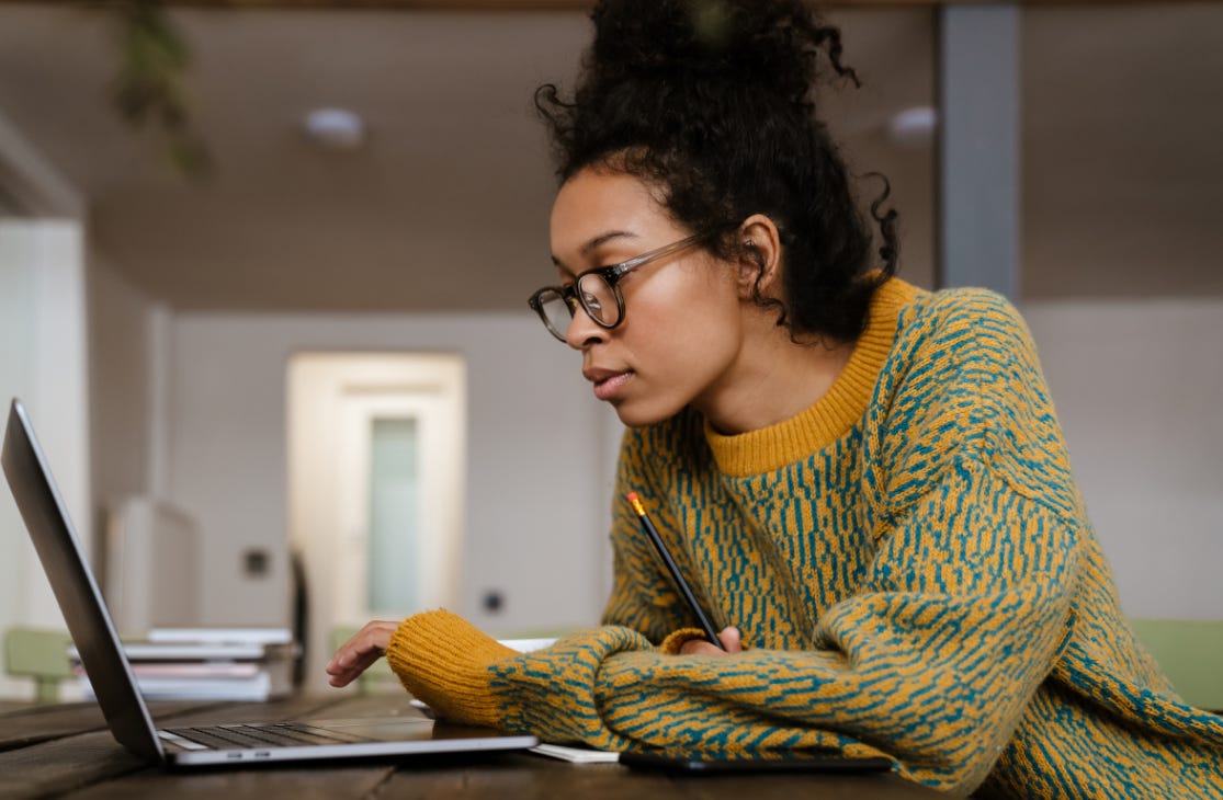 Woman with ADHD in a loose sweater and messy bun hyperfocusing intently on her laptop