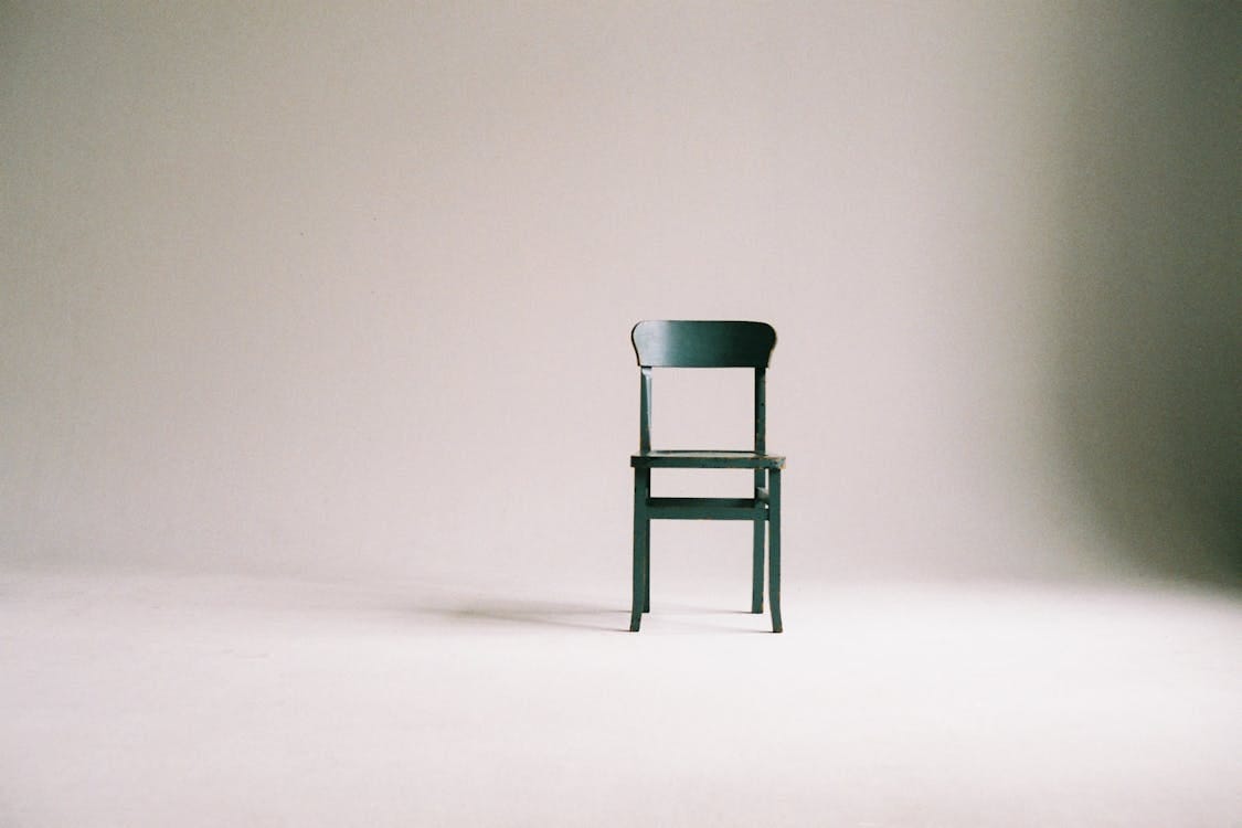 Free A single black chair in a minimalistic studio setting with a neutral backdrop. Stock Photo