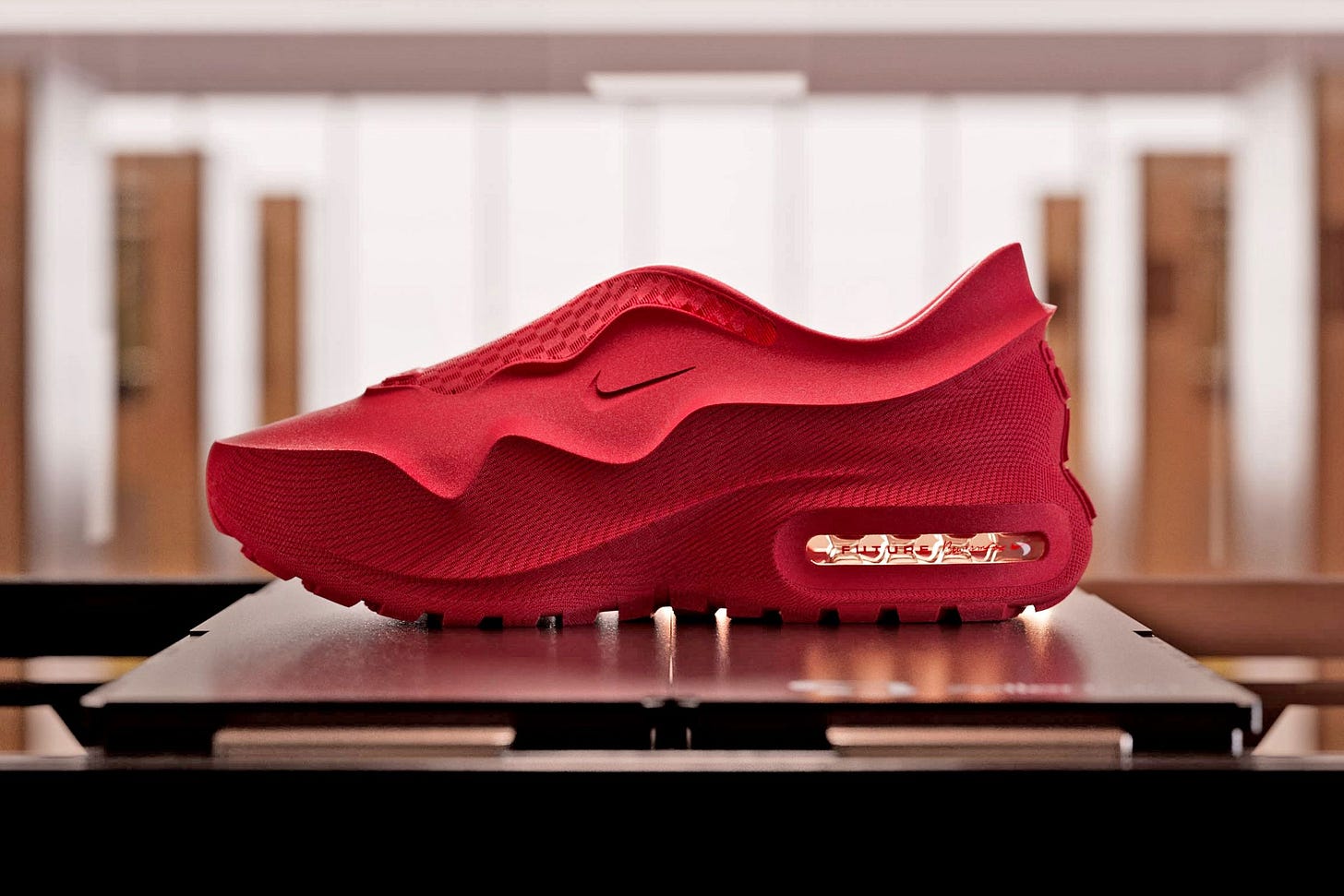The Nike Air Max 1000 shoes in a red finish&nbsp;sitting on the bed of a 3D printer.