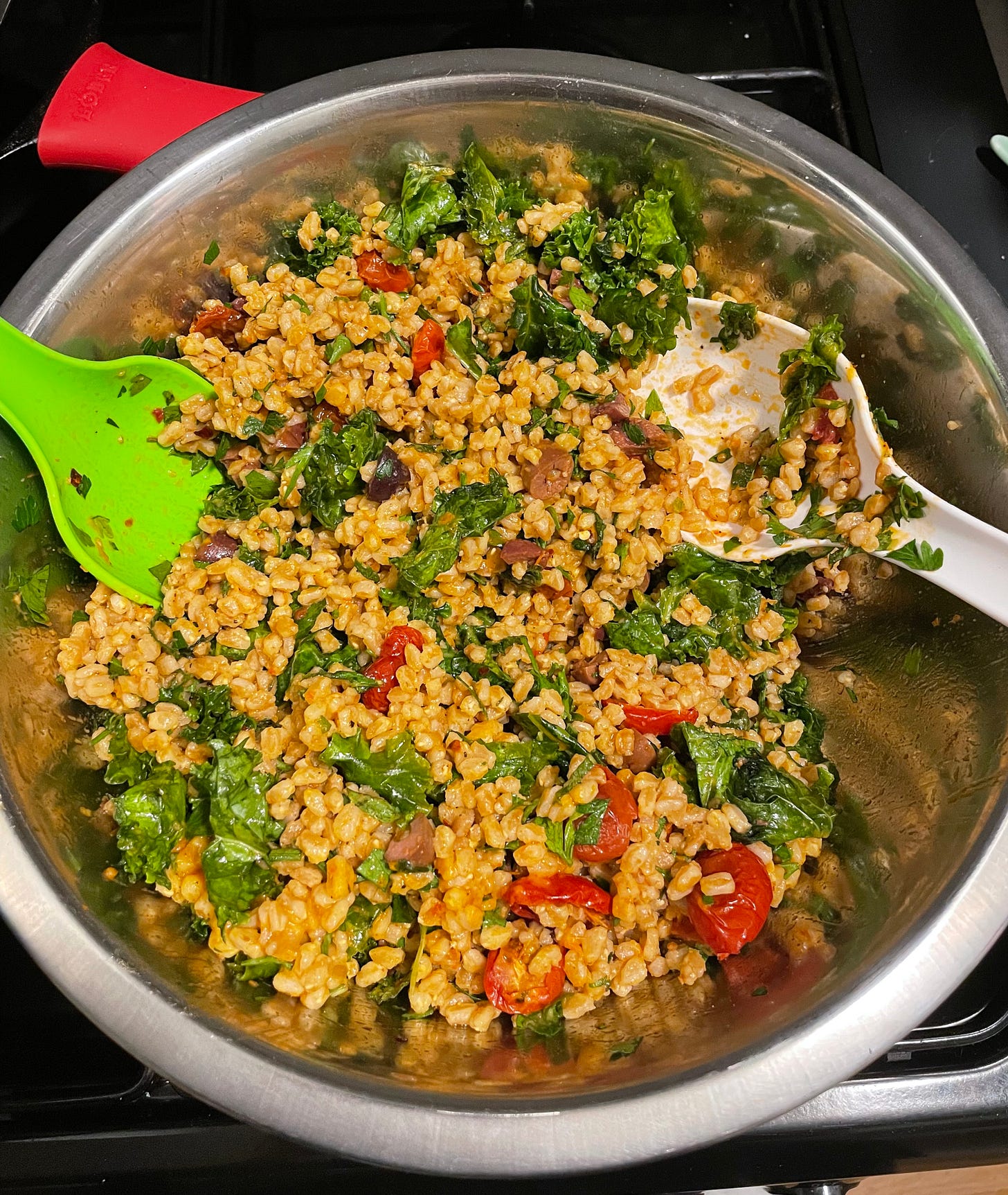 bowl of farro salad with tomatoes, kale, olives, and herbs