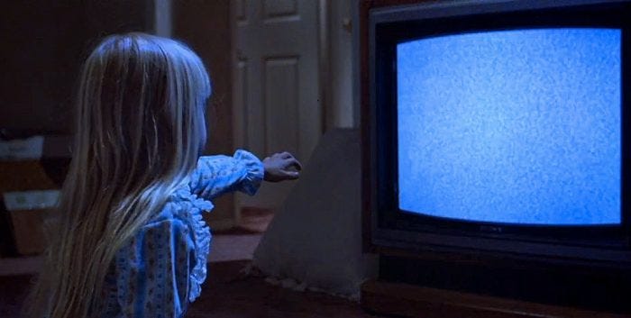 screen shot from poltergeist of girl reaching out to a TV with static on it