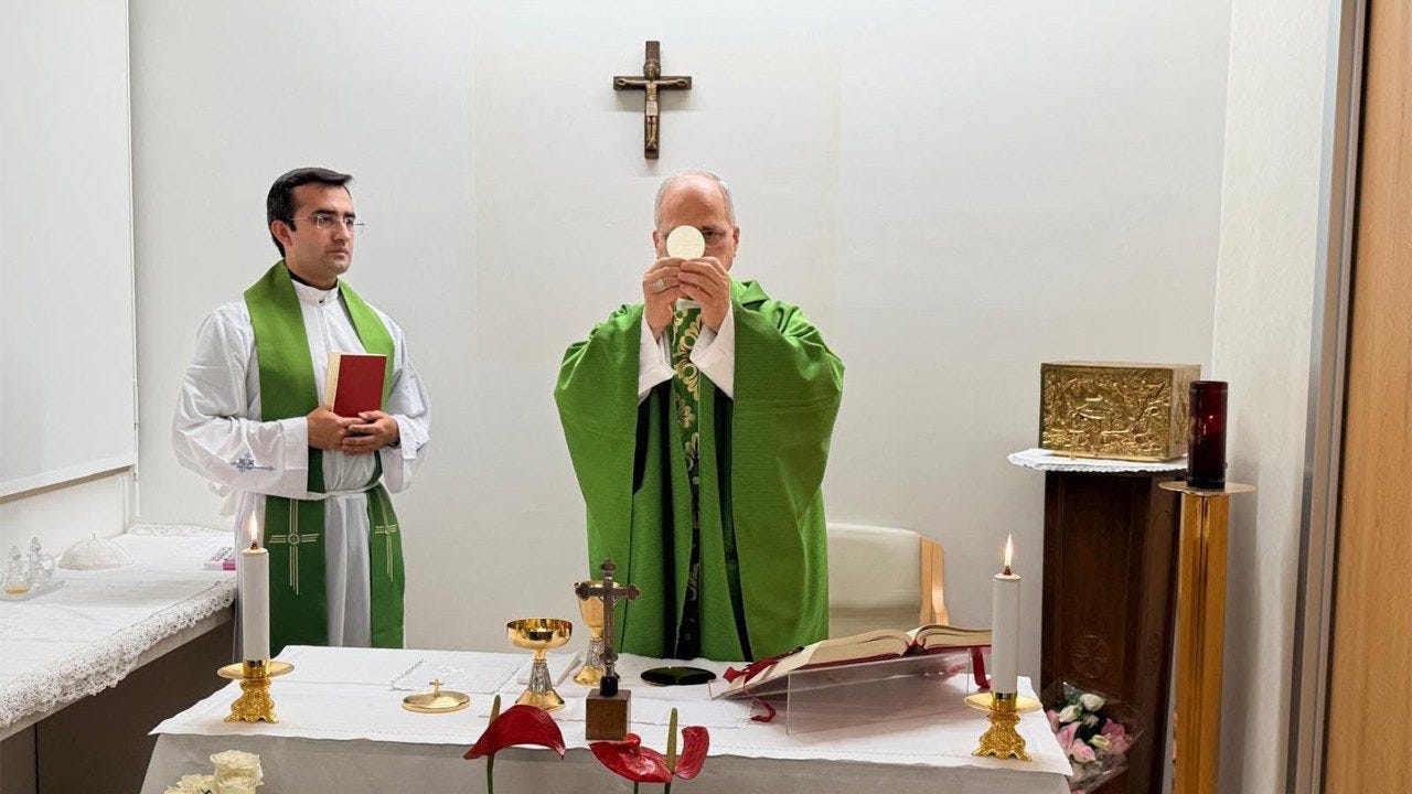 Pope Leo XIV elevates the host at the altar as an assisting priest stands beside him