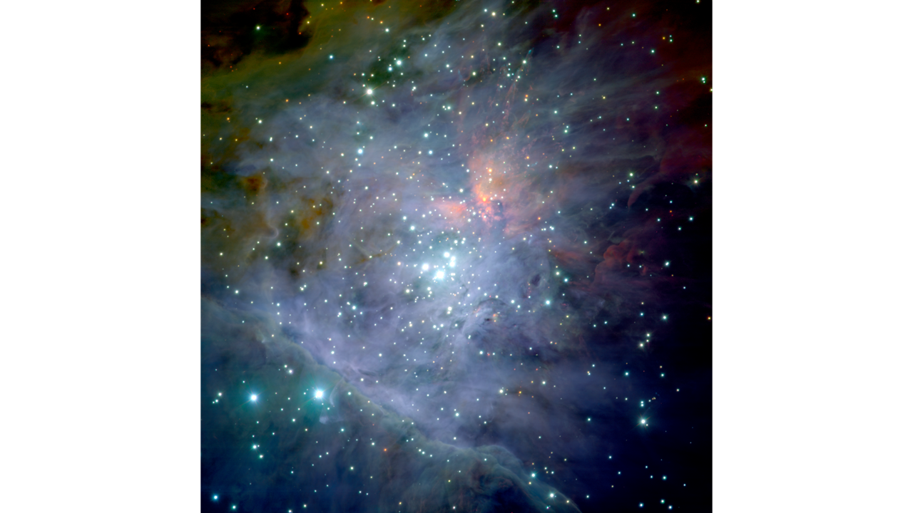 A blaze of color fills the scene, which has a black background with blue pinprick of light, which are stars, scattered throughout. Trapezium stars appear near the center, amid the Trapezium Cluster. They are tightly knotted, slightly larger, and also very bright. A few very bright blue stars also appear at bottom left. The stars are largely covered by an irregular gaseous glow, set off in light purple, but complemented by light green at top right, pink toward the top left, and a blue line crossing the bottom third at an angle that starts higher at left, and ends lower at right. A blaze of color fills the scene, which has a black background with blue pinprick of light, which are stars, scattered throughout. Trapezium stars appear near the center, amid the Trapezium Cluster. They are tightly knotted, slightly larger, and also very bright. A few very bright blue stars also appear at bottom left. The stars are largely covered by an irregular gaseous glow, set off in light purple, but complemented by light green at top right, pink toward the top left, and a blue line crossing the bottom third at an angle that starts higher at left, and ends lower at right.