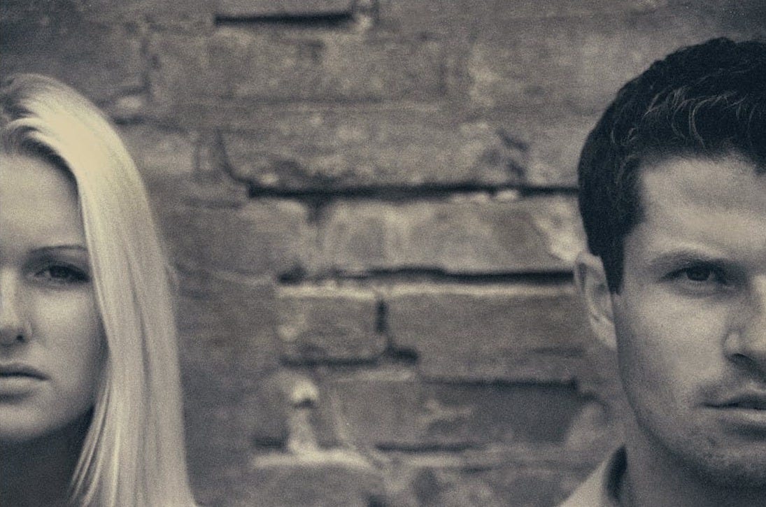 Free Close-up artistic portrait of a couple posing against a brick wall, highlighting their facial expressions. Stock Photo