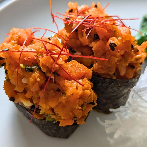 Three gunkan maki sushi pieces, each featuring a different plant-based topping: natto, spicy carrot tuna, and amaranth caviar. Each piece is wrapped in nori around a bed of rice, with the toppings held neatly on top.