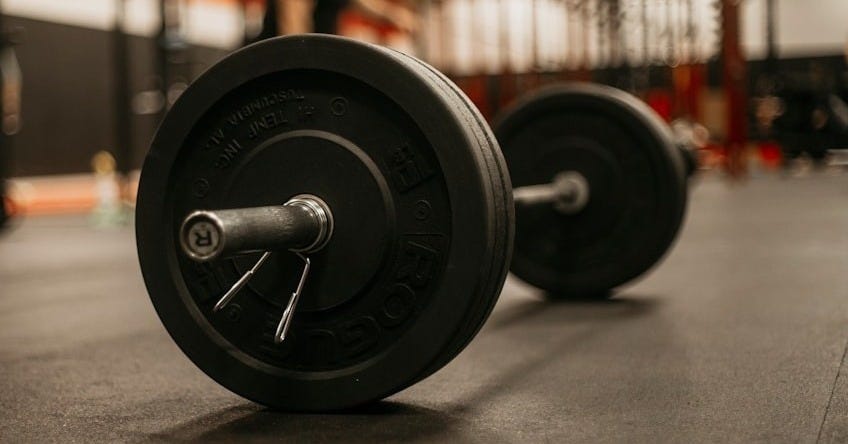 a man squatting down next to a barbell in a gym