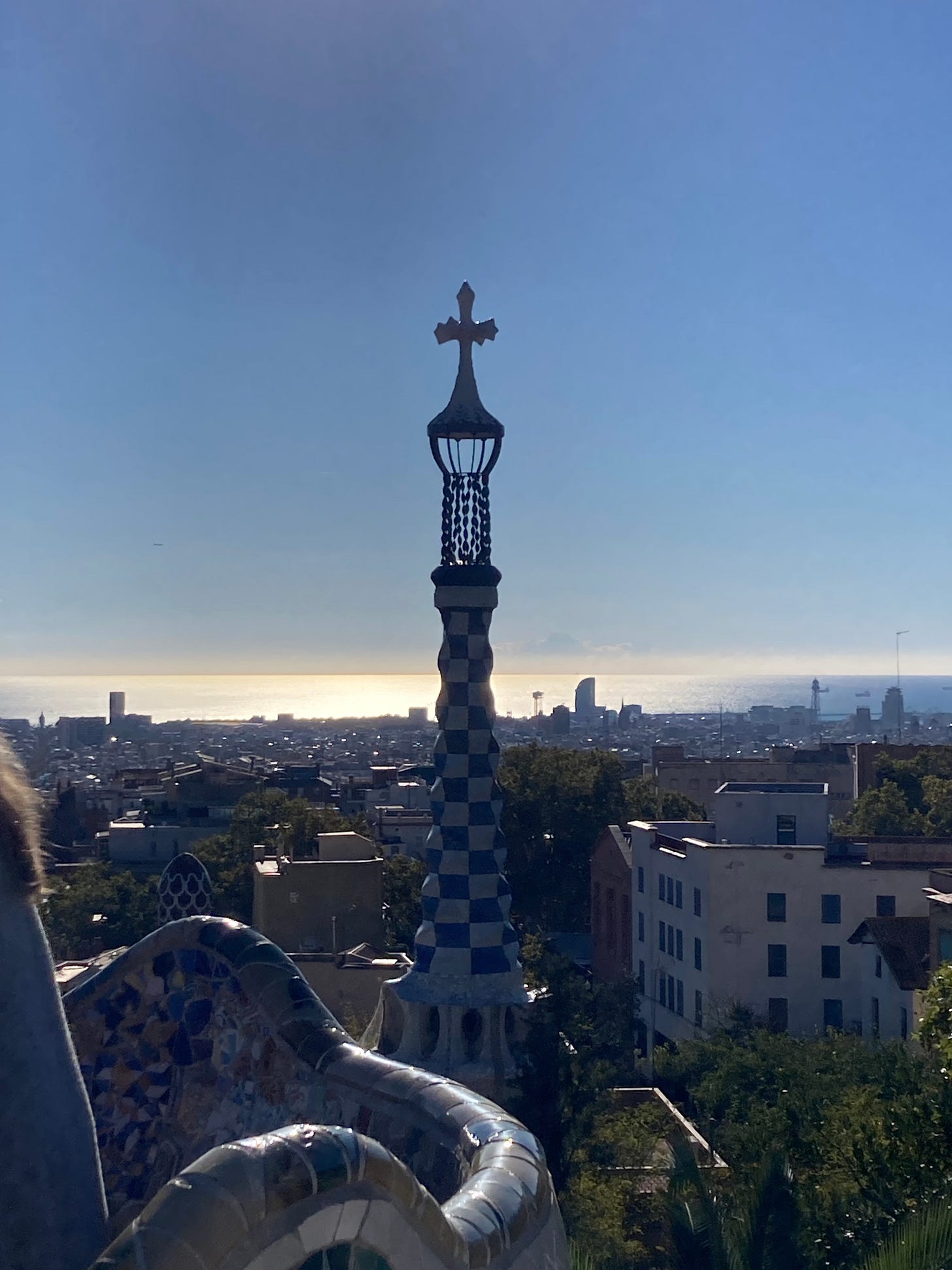 Buried No More: a metal cross atop a church backlit by the rising sun in Barcelona