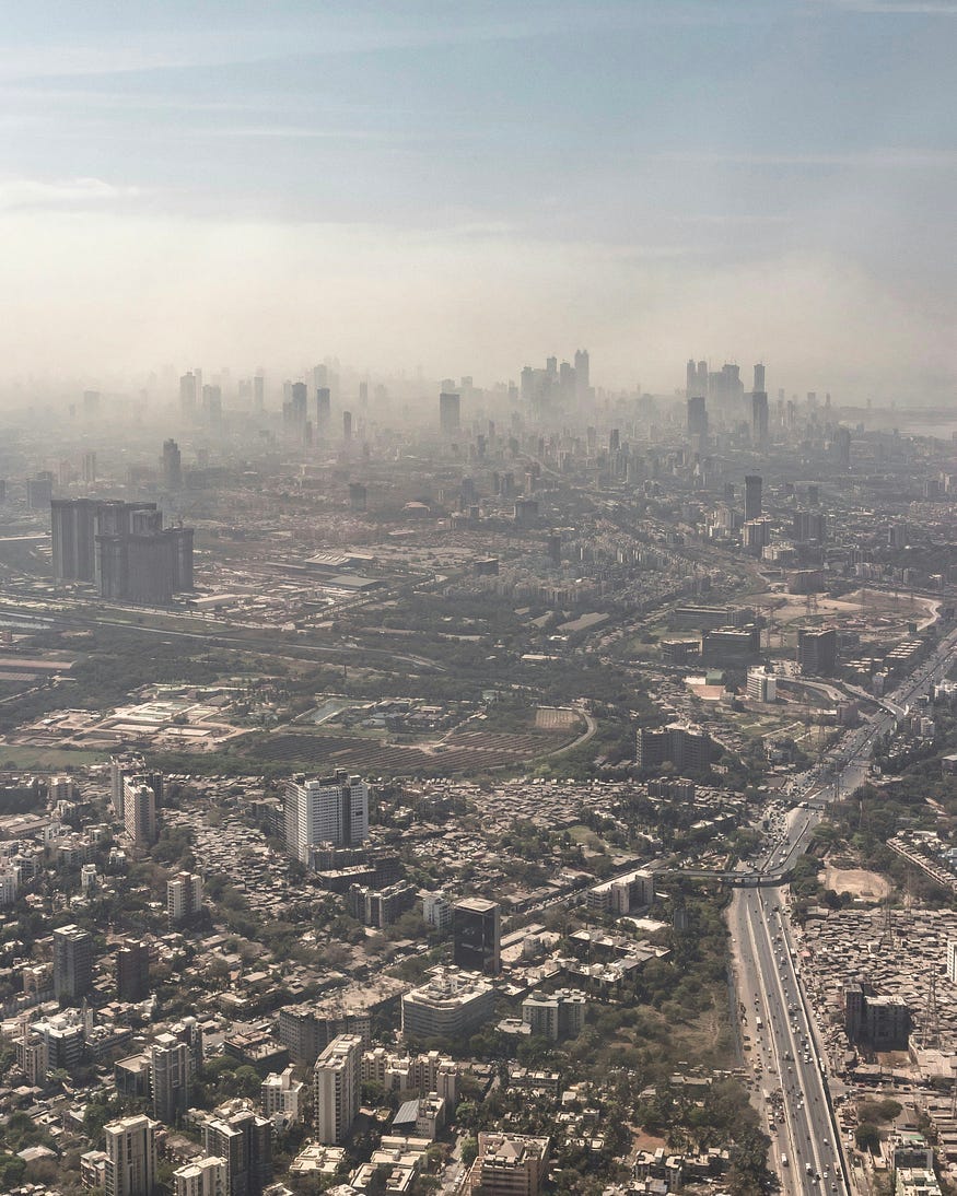 A city full of traffic, buildings and roads. Personal vehicles fill the air with smog, which could be reduced by environmentally friendly public transportation.