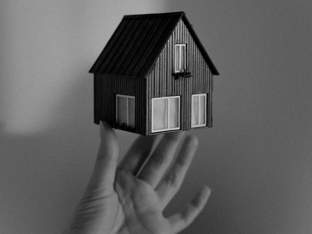 A person holding a small house in their hand A person holding a small house in their hand