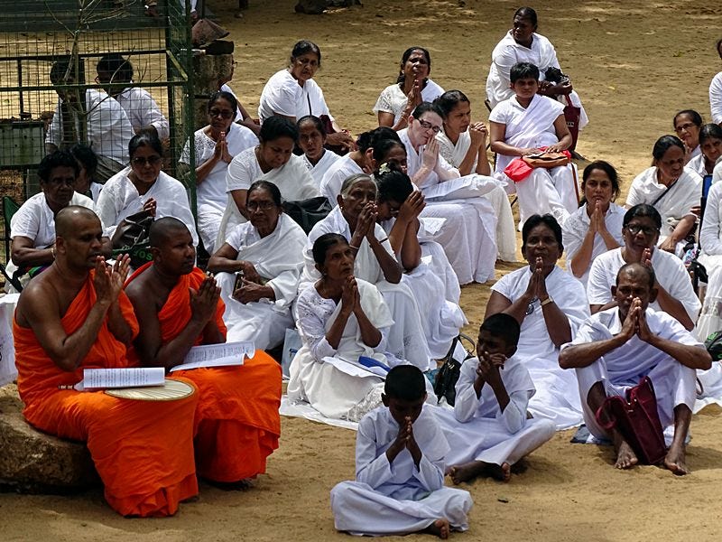 Group of people dressed in white praying together at a religious site