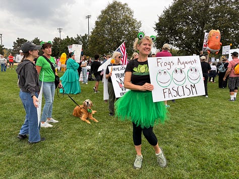 Various protesters and dogs with signs at a NO KINGS rally