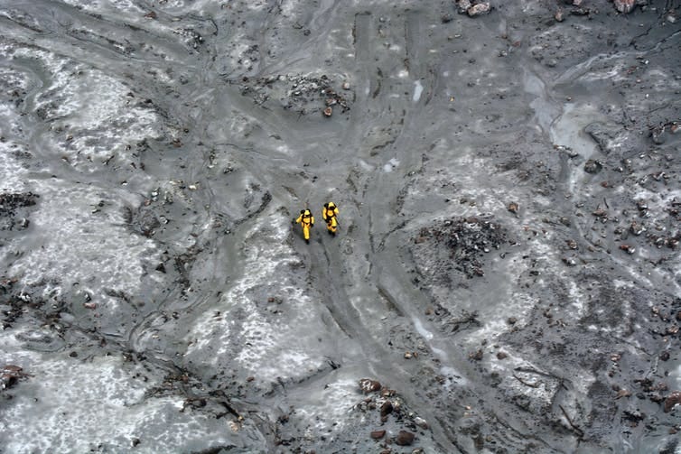 Two rescuers seen walking across an ash field on Whakaari White Island in December 2019. Two rescuers seen walking across an ash field on Whakaari White Island in December 2019.