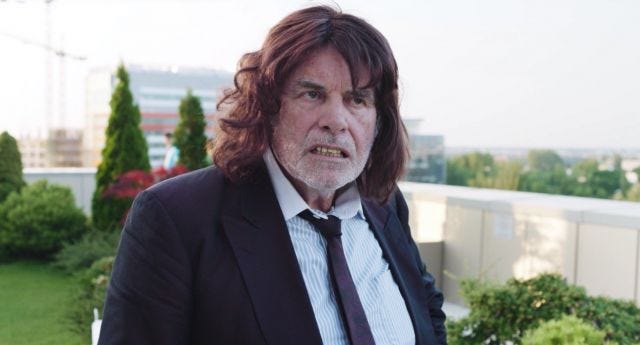 Man in long red wig in corporate garden Man in long red wig in corporate garden