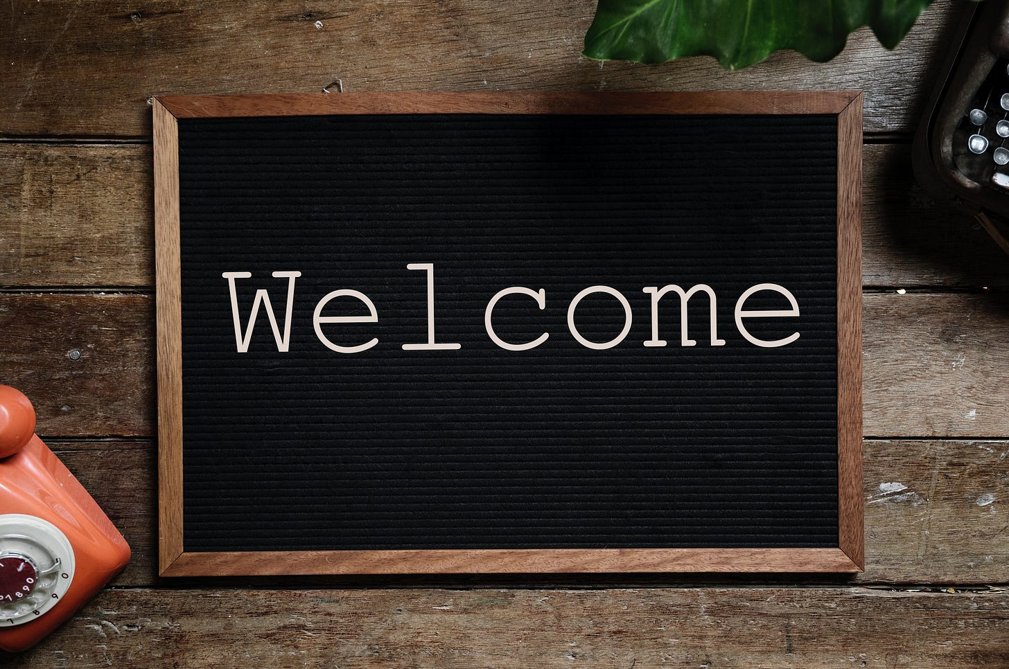 A black pinboard with the word Welcome written on it.
