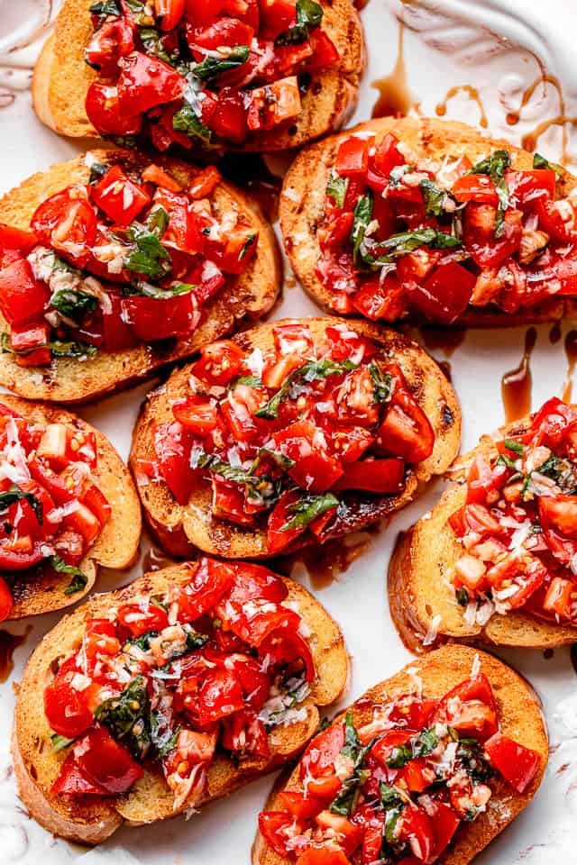 bread slices topped with tomato salad and served on a white platter bread slices topped with tomato salad and served on a white platter