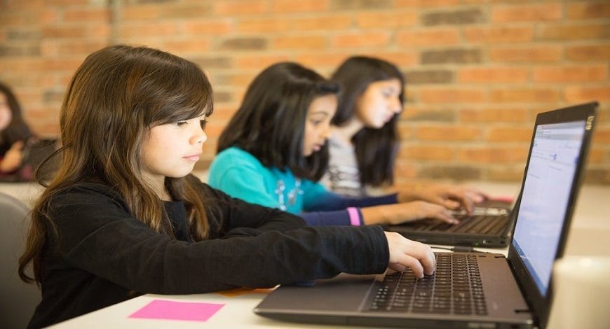 picture of three young girls using computers in a classroom setting.
