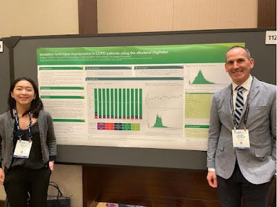 Two people standing by a green conference poster with text and graphs.