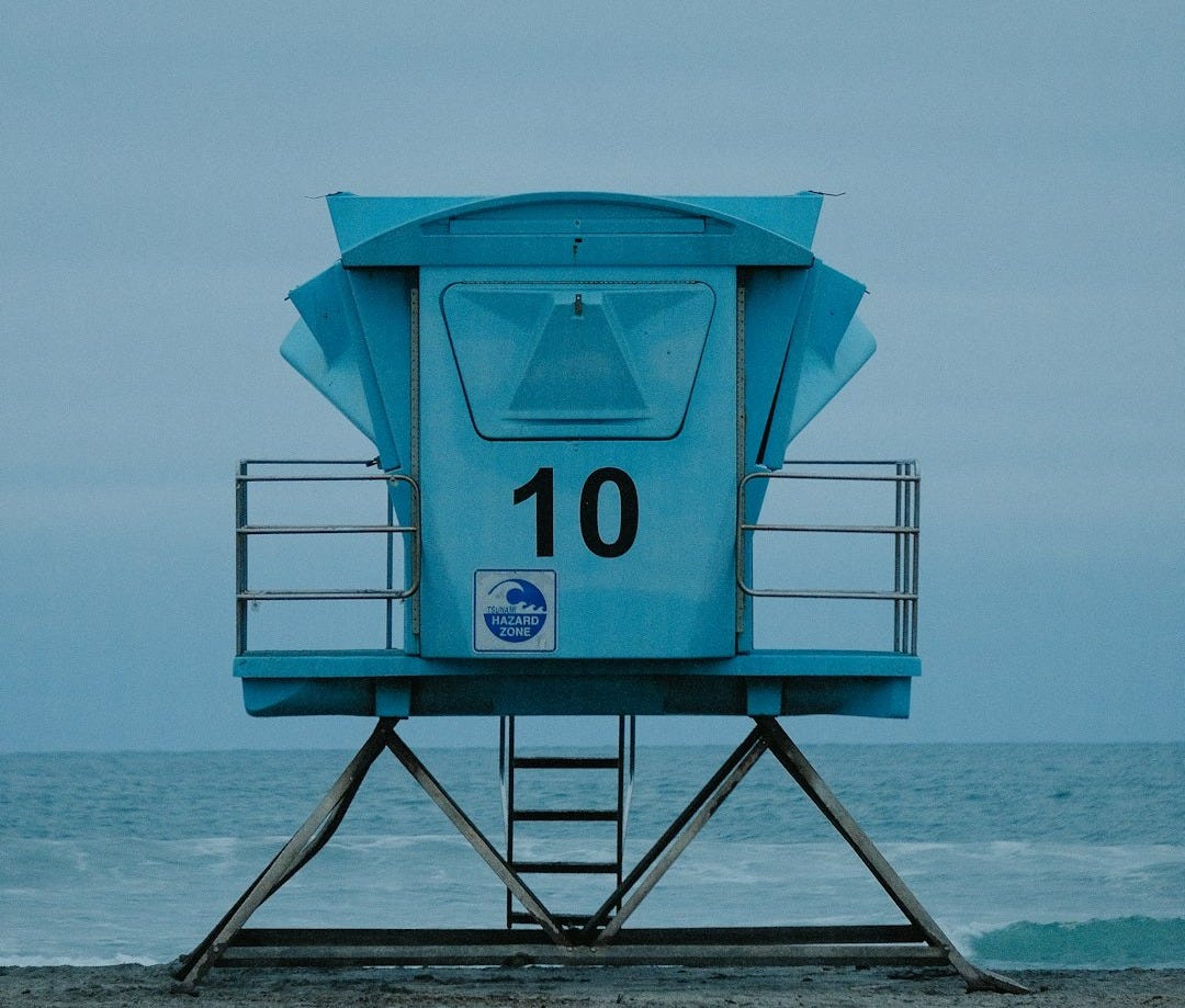 a lifeguard tower sitting on top of a sandy beach a lifeguard tower sitting on top of a sandy beach