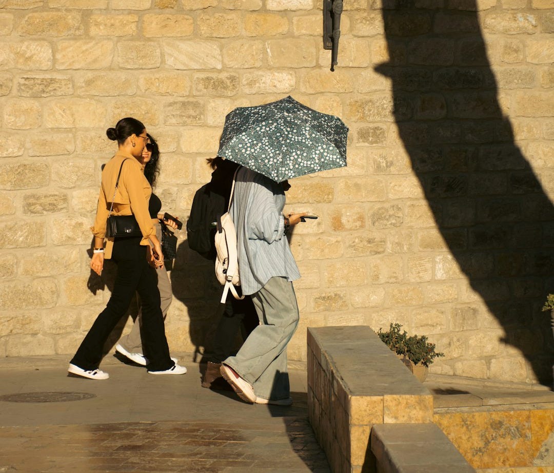 A group of people walking down a sidewalk holding umbrellas