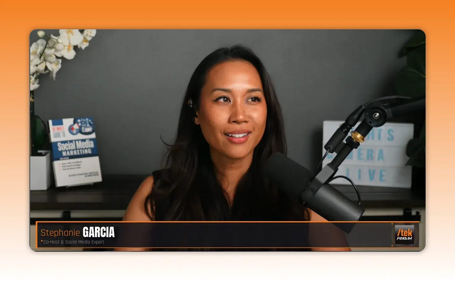 Stephanie Garcia speaking to camera with studio microphone and branded books in the background