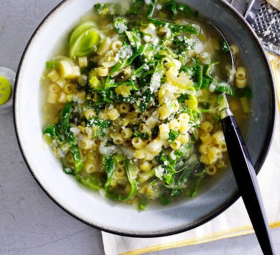 A bowl of Spring Vegetable Soup with Lemon served with a spoon in the bowl