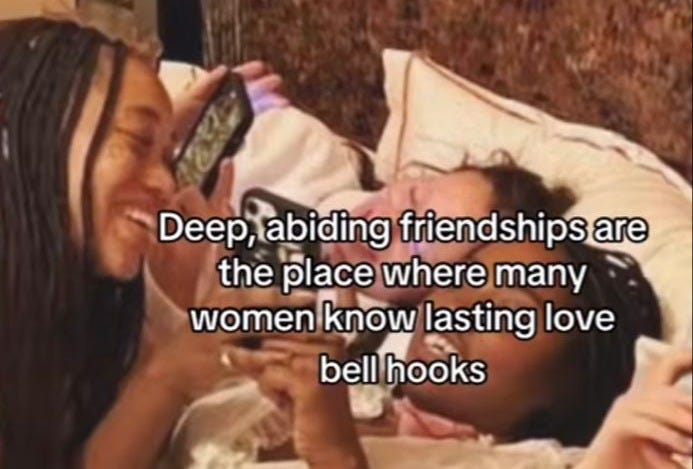 This may contain: two women laying in bed and one is holding a cell phone