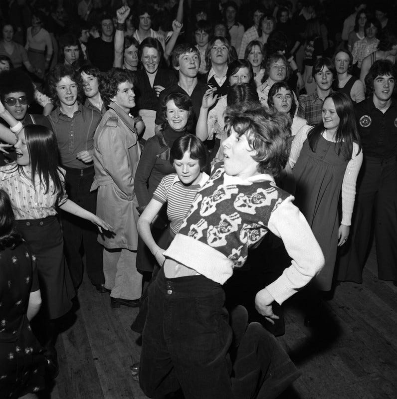 A crowd of people enthusiastically dancing in the 1970s