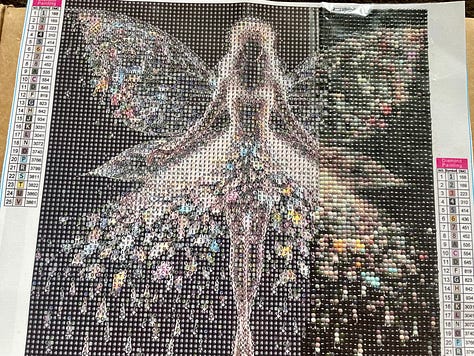 3 photos of 'diamond art' creations where small plastic gemstones in varying colours are slowly added to paper in a specific pattern. It is methodical and soothing but also fun and colourful art. The photos feature an irredescent fairy, a colourful moon and sun illustration with stars. planets and butterflies for decoration, plus a colourful fruit scene with watermelon, dragonfruit, cherries, bananas, oranges and strawberries, with the sticking pen tool in view.
