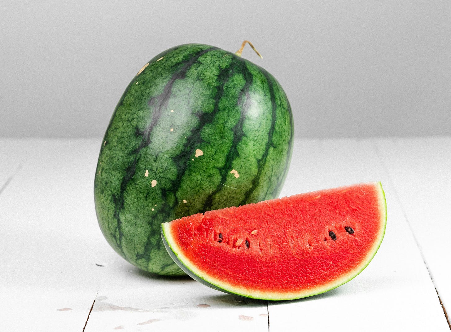 Un'anguria con un pezzo di anguria tagliata davanti.