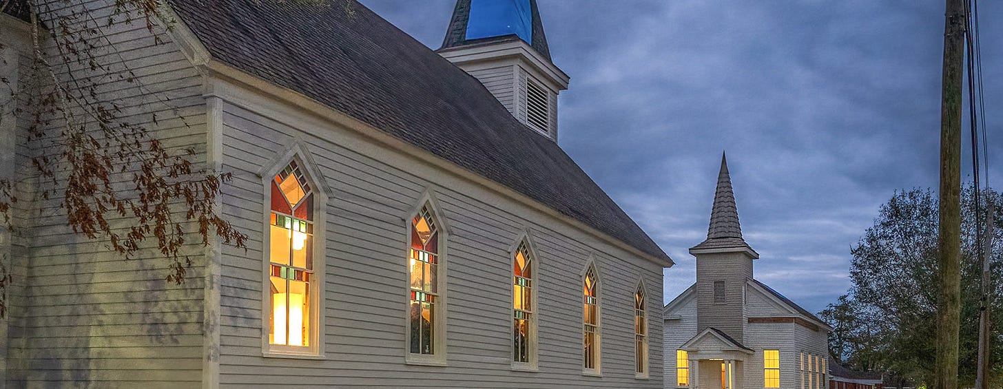 two white churches with steeples facing each other after dark lights on inside