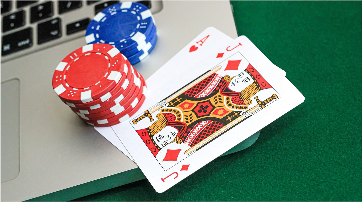 A pair of playing cards under a small stack of poker chips on the edge of a laptop A pair of playing cards under a small stack of poker chips on the edge of a laptop