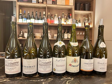 bottles of French wine from two tastings. Wines of Burgundy and the Loire Valley. Plates of appetizers on a wooden table.