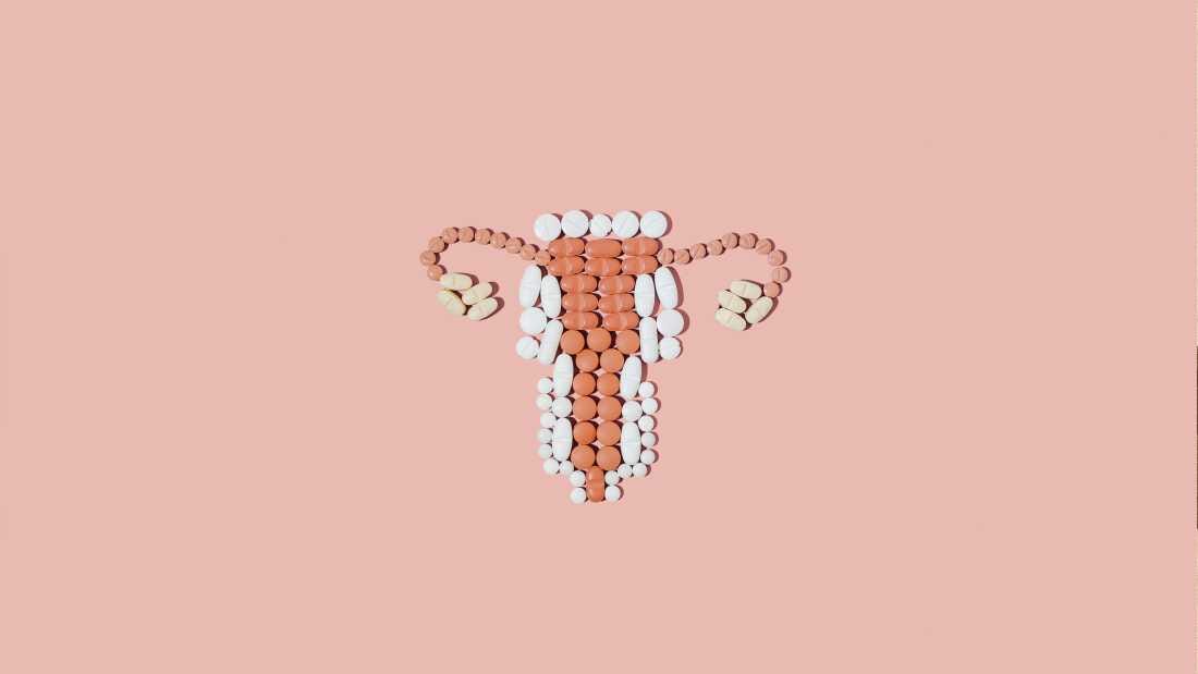Pills in shape of female reproductive system on a pink background
