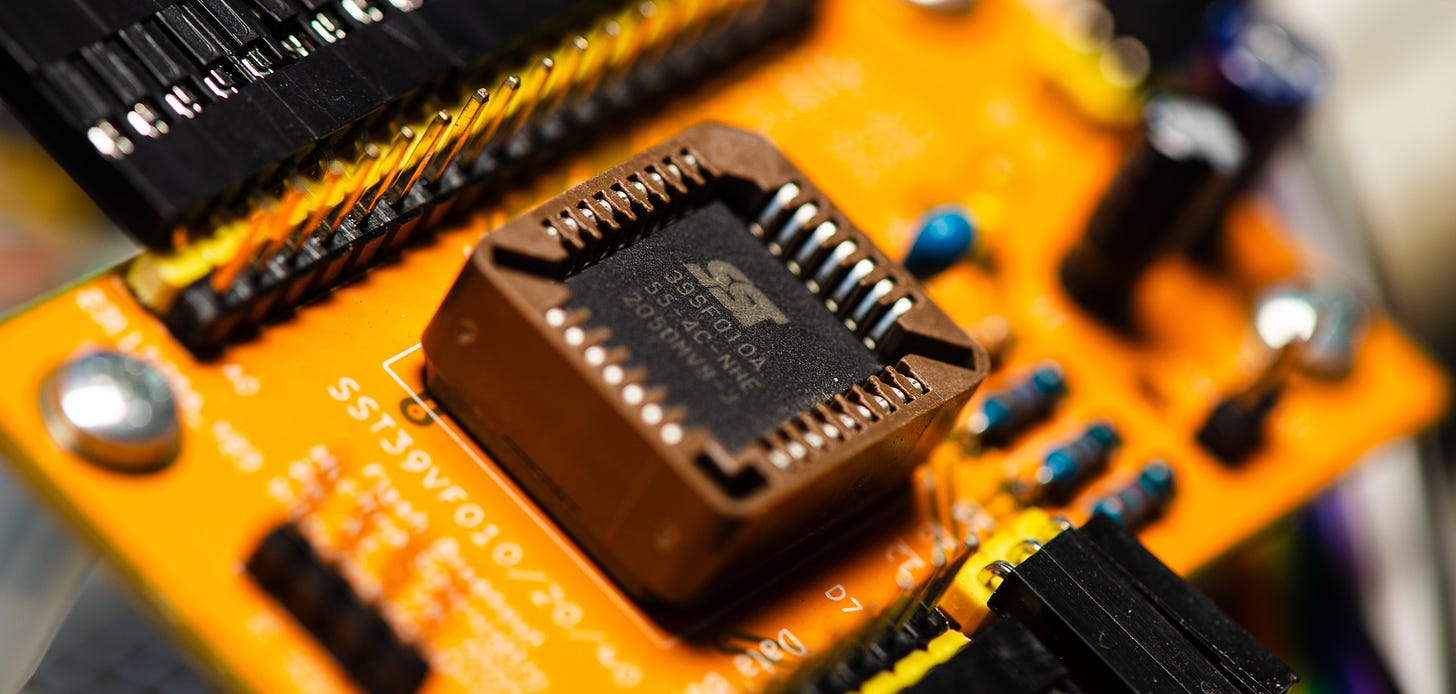 A close-up photograph of a square computer chip in a socket on a yellow printed circuit board. A close-up photograph of a square computer chip in a socket on a yellow printed circuit board.